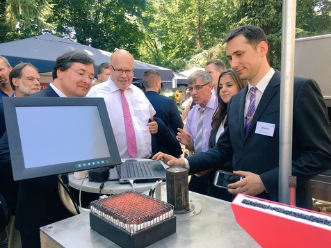 Bundeswirtschaftsminister Peter Altmaier bei seinem Besuch des FEI-Standes: Vojislav Jovicic (rechts) demonstriert die Porenbrennertechnologie. Auch sehr interessiert daran: AiF-Präsident Prof. Sebastian Bauer (links).