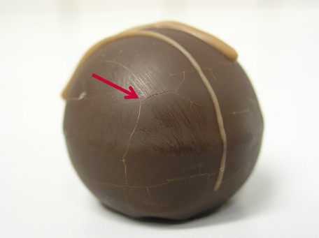 Risse auf der Oberfläche eines Schokoladentrüffels aufgrund osmotoleranter Hefen.