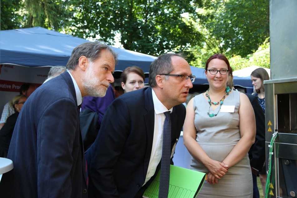 Schauen sich gemeinsam an, wo in dem Backofen die Porenbrenner eingebaut sind: FEI-Geschäftsführer Dr. Volker Häusser und BMWi-Unterabteilungsleiter Dr. Ole Janssen. Rechts: Dr. Ana Zbogar-Rasic von der Universität Erlangen-Nürnberg.