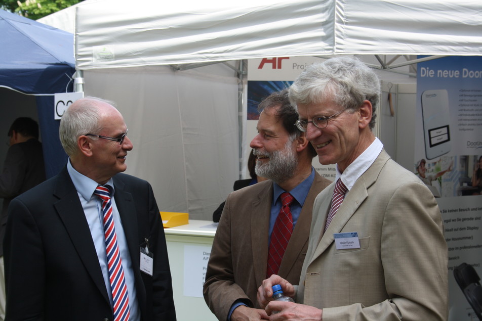 Dr. Reinhard Jensch (BMWi; links) besucht auf seinen Rundgang auch den FEI-Stand.