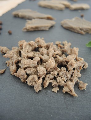 Rehydratisiertes/eingeweichtes Texturat aus 80 % Sesampresskuchen und 20 % Erbsenproteinisolat. Im Hintergrund: Nasstexturat mit 20 % Sonnenblumenpresskuchen und 80 % Erbsenproteinisolat.