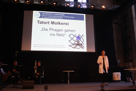 Tatort Molkerei! Doktorandin Meike Samtlebe von der Uni Hohenheim stellt "ihr" IGF-Projekt des FEI beim Science Slam höchst unterhaltsam vor. Tatort Molkerei! Doktorandin Meike Samtlebe von der Uni Hohenheim stellt "ihr" IGF-Projekt des FEI beim Science Slam höchst unterhaltsam vor.